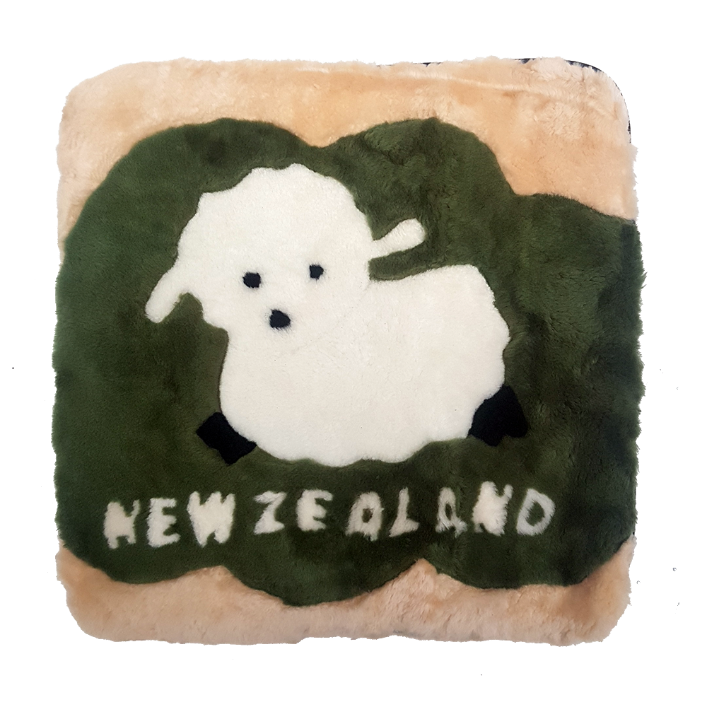 A square-shaped cushion with a green background featuring a white baby lamb on top of a grass-like pattern. The cushion also has the text 'NEW ZEALAND' at the bottom.