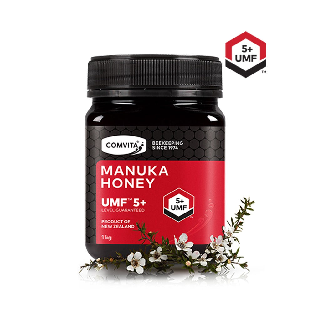 A jar of Comvita UMF 5+ Manuka Honey with a label showing the brand and product details, set against a background with a blurred image of flowers.