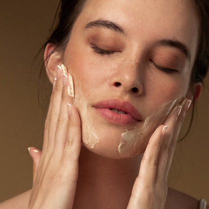 A woman applies Antipodes Hallelujah Lime & Patchouli Facial Cleanser on her face