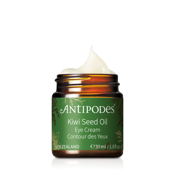 A jar of Antipodes Kiwi Seed Oil Eye Cream with a pump dispenser, predominantly orange in color with a green label, indicating it is vegan-friendly.