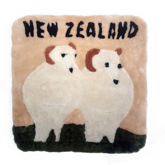 A square-shaped cushion featuring a design of two white sheep on a beige background with the text 'NEW ZEALAND' at the top.