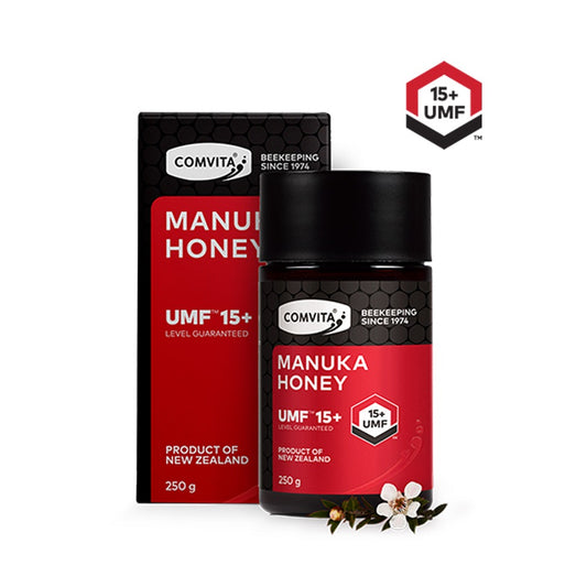 Packaging of Comvita UMF 15+ Manuka Honey 250g. The package includes a black and red box with a transparent window showing a jar of honey, and a black lid with a white label.